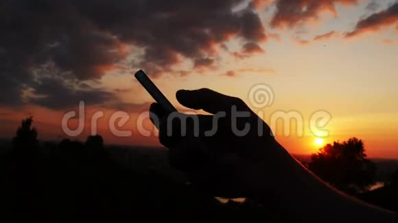 在日落的天空背景下用手机说话的人视频的预览图