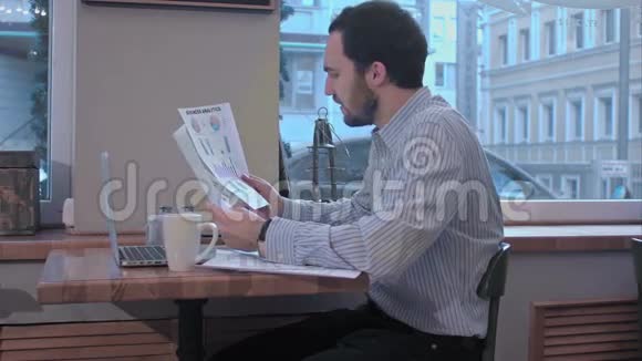 咖啡馆里的商人饶有兴趣地阅读着一份合同文件视频的预览图