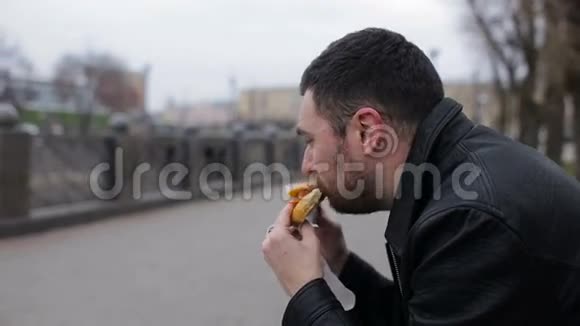 成年男子在城市里的长椅上吃热狗视频的预览图