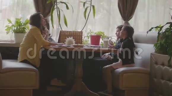 妈妈和小朋友在快餐店靠窗的慢动作视频妈妈和孩子们玩得开心坐着聊天视频的预览图