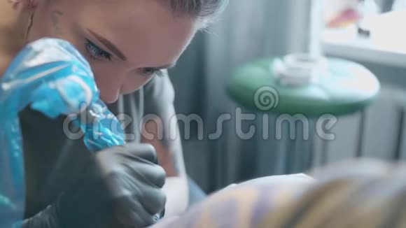 女人一个纹身艺术家在沙龙里做纹身视频的预览图