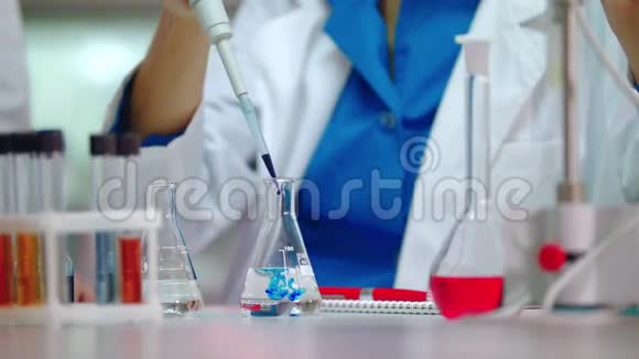 女科学家把试剂倒进实验室的烧瓶里做化学反应的科学家视频的预览图