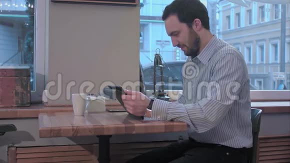 有胡子的商人在咖啡店用平板电脑视频的预览图