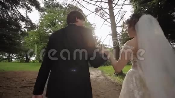优雅的新娘穿着漂亮的白色婚纱公园里有英俊的新郎绿色背景视频的预览图