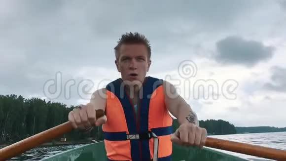 一个坐在船上划木桨的年轻人人身上的救生衣视频的预览图