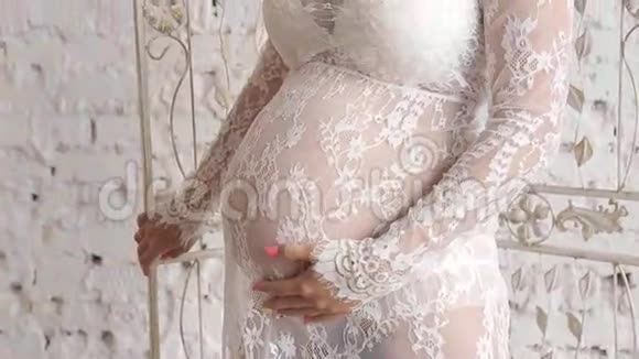 美丽的孕妇穿着连衣裙站在窗口视频的预览图