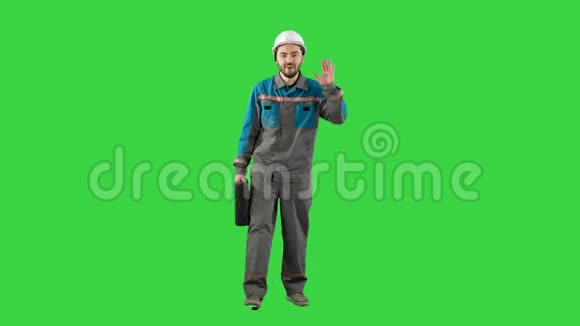 戴着头盔带手提箱的建筑工人在绿色屏幕上的摄像机上说Chroma键视频的预览图