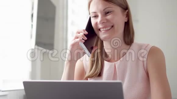 忙碌的女人坐在家里拿着笔记本电脑和智能手机通过手机在屏幕上讨论项目视频的预览图
