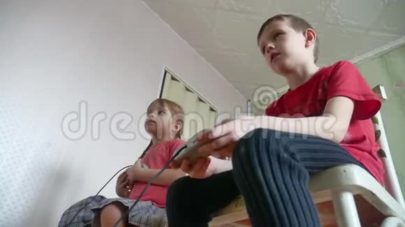 孩子们在室内控制台上玩电子游戏控制器男孩和女孩在网上玩游戏视频的预览图