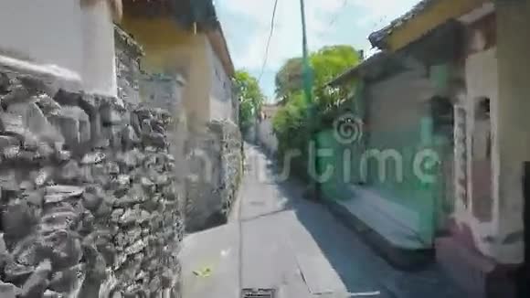 穿过传统巴厘岛村庄的景观典型的建筑在街道内狭窄的小路上场景视频的预览图