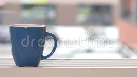 蓝色的热饮杯站在窗台上雪花飘落视频的预览图