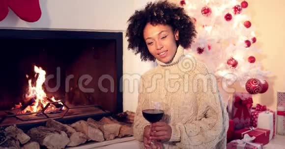 漂亮的女人在壁炉旁拿着酒杯视频的预览图