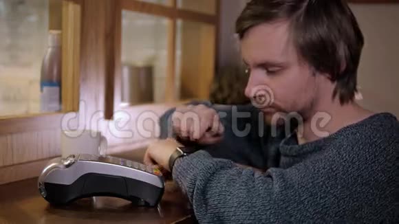 男人用智能手表在木桌上表达工资现代咖啡厅NFC技术视频的预览图