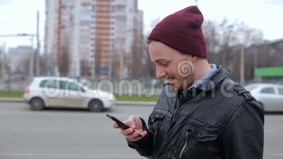 有魅力的男人在城市汽车站等着看手机视频的预览图