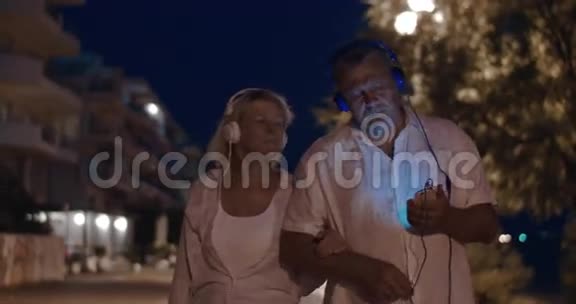 年长夫妇在夜间散步时听音乐视频的预览图