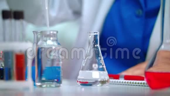 实验室医生用吸管将透明液体倒入实验室瓶中视频的预览图