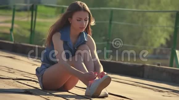 女孩系鞋带坐在浮桥上的女孩老锈的铁视频的预览图