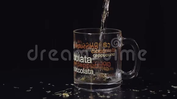 用有机干绿茶叶将沸水倒入玻璃杯中准备绿茶慢动作黑色背景视频的预览图