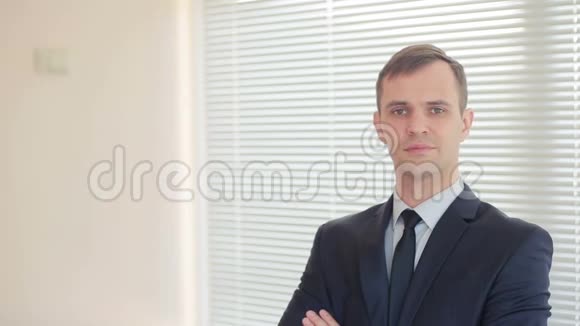 年轻的商人站在一间办公室的百叶窗背景上在镜头上竖起大拇指视频的预览图