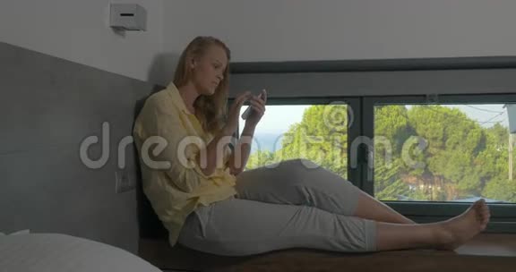 坐在窗台上用电话的女人视频的预览图