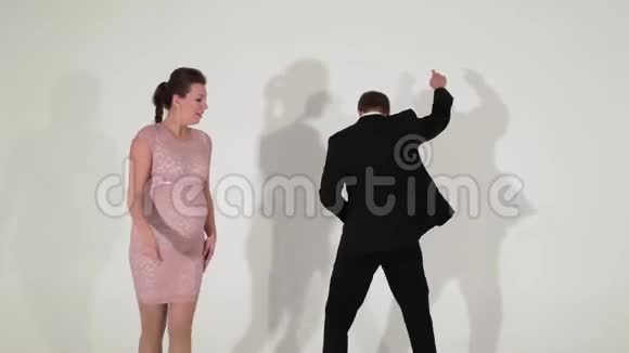 穿着黑色西装穿着衬衫的帅哥和孕妇正在灯光室跳舞视频的预览图