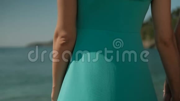 在海岸上有一个穿着绿松石长裙的女人视频的预览图
