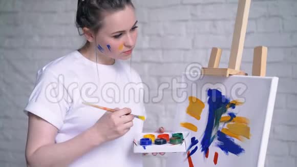 穿围裙的年轻女艺术家在艺术工作室画画布视频的预览图