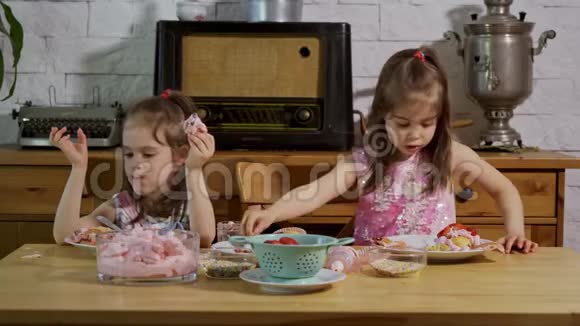 两个小女孩穿上奶油在木桌上装饰美味的纸杯蛋糕视频的预览图