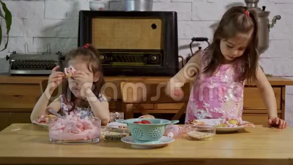 两个可爱的小女孩穿上奶油装饰美味的纸杯蛋糕视频的预览图