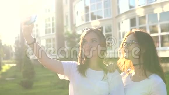 美丽的女孩朋友带着自拍在城市日落强烈的背光视频的预览图