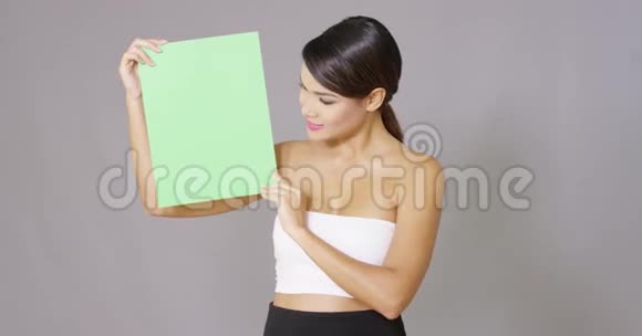 在灰色背景下拿着一张空白卡片的女人视频的预览图