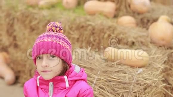 小女孩坐在干草上装饰着南瓜等待假期视频的预览图
