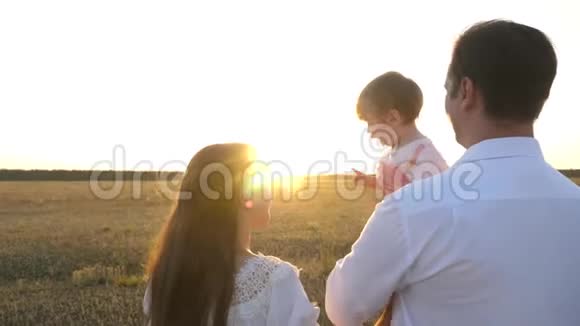 一家人在日落时和婴儿玩日落时分爸爸和妈妈和她的女儿抱在怀里散步父亲视频的预览图