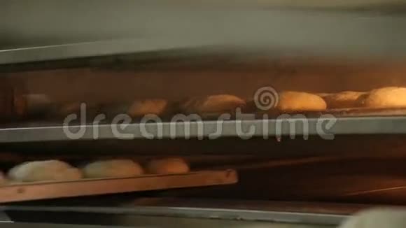 面包师穿制服拿着铲子从烤箱里拿出刚出炉的面包视频的预览图