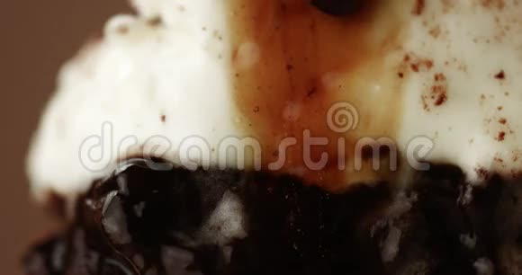 一块巧克力蛋糕放在叉子上上面有白色奶油和液体视频的预览图