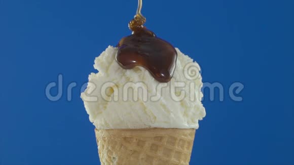 香草冰淇淋勺蓝色背景下流动巧克力酱4K视频的预览图