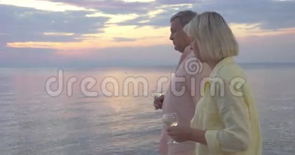 带着酒杯的成熟情侣走在海边视频的预览图