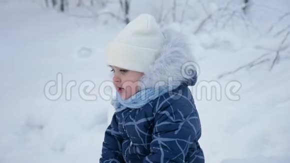 冬天孩子们坐在树林里的雪地上视频的预览图