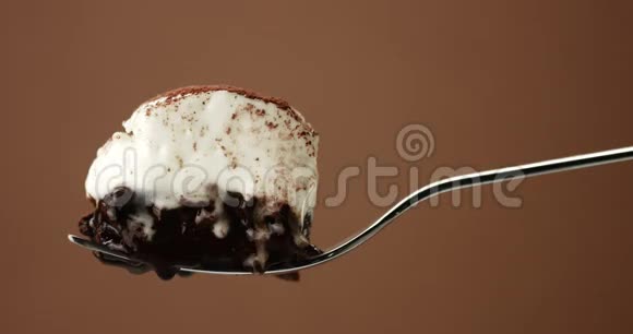 一块巧克力蛋糕放在叉子上上面有白色奶油和液体视频的预览图