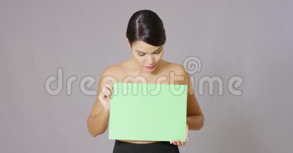 在灰色背景下拿着一张空白卡片的女人视频的预览图