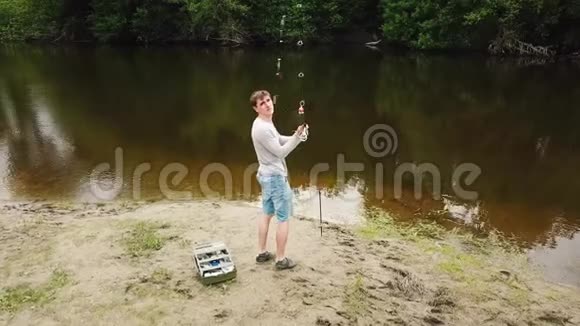 河岸上拿着鱼竿的渔夫渔夫钓到一条鱼农村逃亡的概念视频的预览图