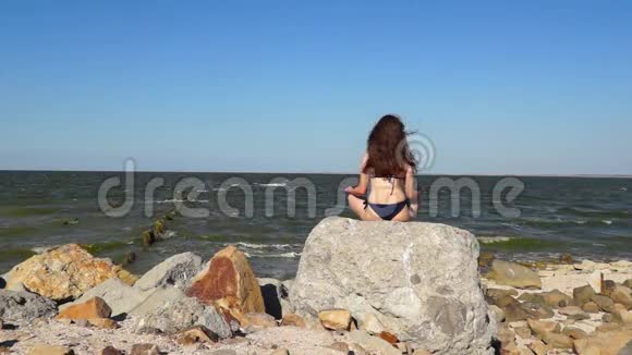 女孩在海边的石头上放松视频的预览图