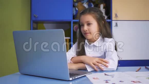 在图书馆学习的女孩用笔记本电脑做课后作业有设备的小学儿童视频的预览图