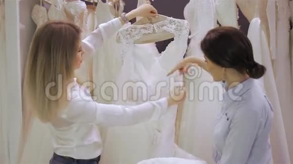 女店长在婚纱店帮新娘挑选服装关注女孩视频的预览图