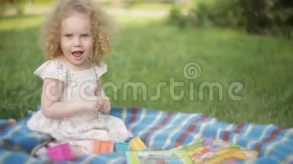 公园里蜷曲的女孩在毛毯上玩耍视频的预览图