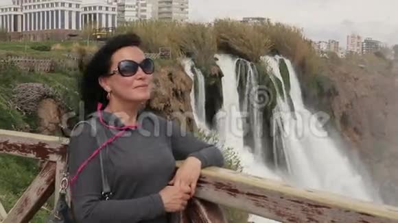 妇女站在公园的桥上背景是土耳其安塔利亚的Duden瀑布视频的预览图
