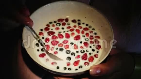 把蓝莓草莓和牛奶混合在一起的手的特写镜头视频的预览图