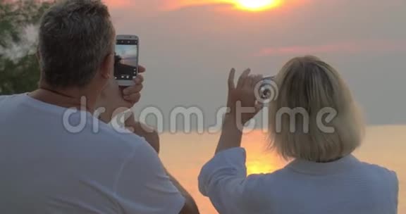 人们在智能手机上拍摄海上日落视频的预览图