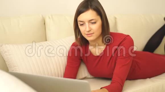 漂亮优雅的女人躺在酒店房间的沙发上用笔记本电脑工作视频的预览图