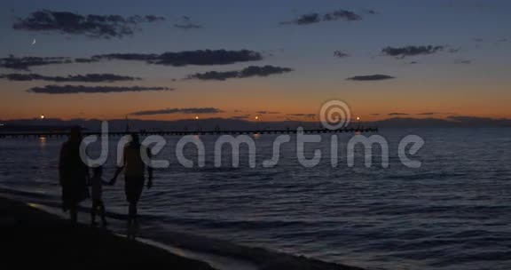黄昏时父母和孩子在海边散步视频的预览图